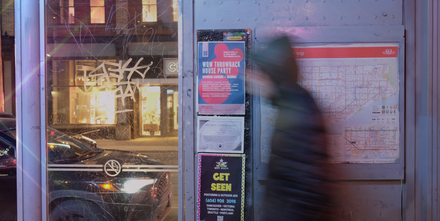 Posters distributed in bus shelter with a person walking by - Skyline City Media covers poster distribution all over Toronto