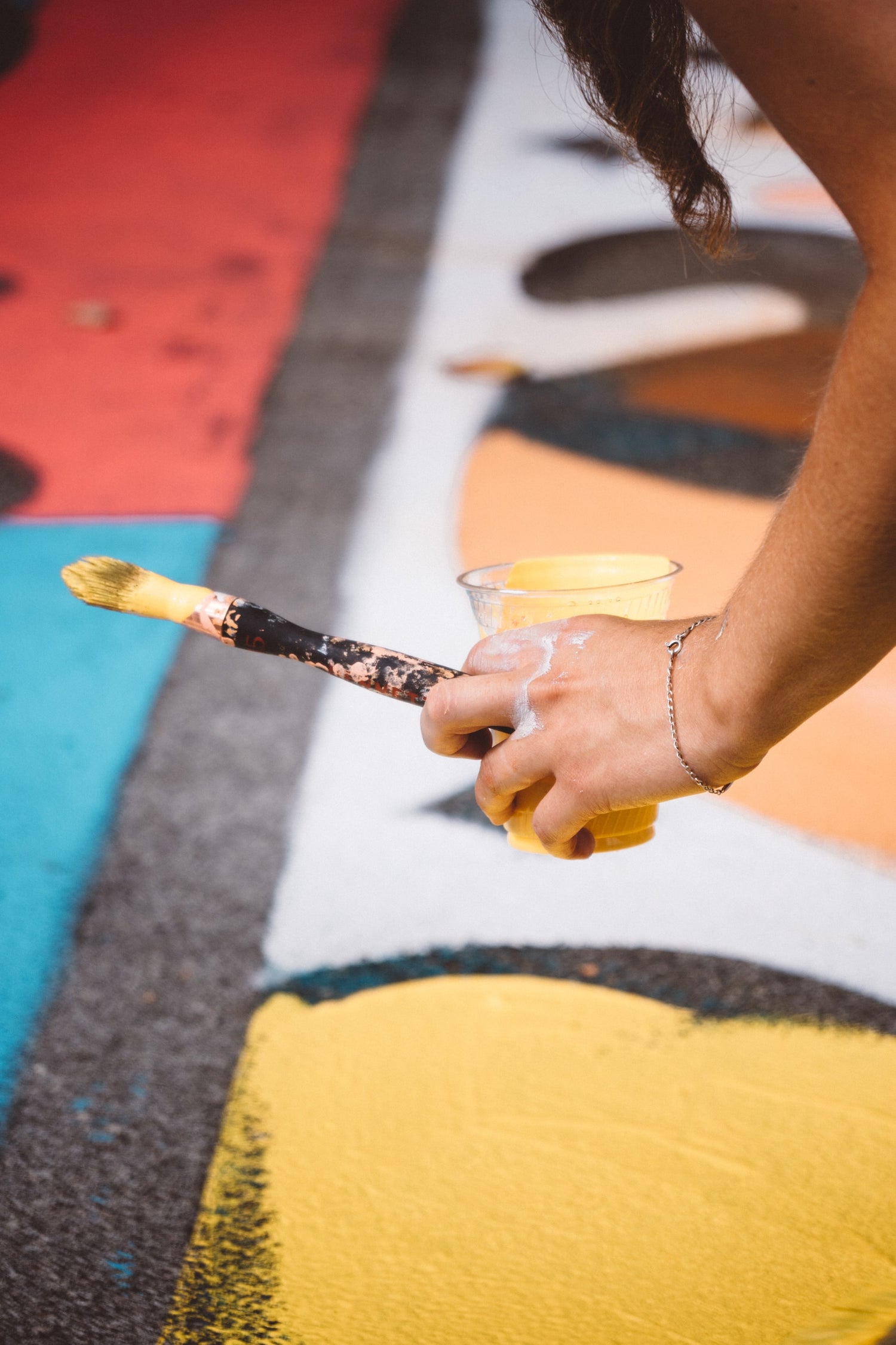 Closeup of an artist live painting a mural painting for the public at Vancouver Mural Fest with yellow paint, custom murals available. Photo by Jaunt and Joy on Unsplash